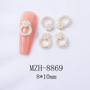 Vue macro de bijoux d'ongles en cœur doré avec perles 8x10mm sur des ongles pêche