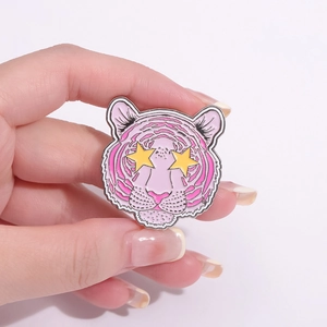 Pin de esmalte de tigre rosa y morado con ojos de estrella amarillos en mano
