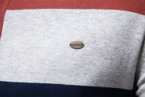 Detail eines mehrfarbigen Streifenstricks mit metallenem Markenlogo auf einem Herren-Polo