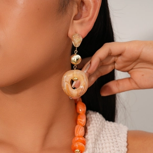 Close-up of vintage resin long drop earrings with gold metal accents on a model