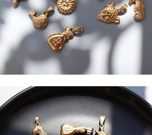 Detailed macro view of 18K gold-plated titanium steel animal charms on a ceramic tray