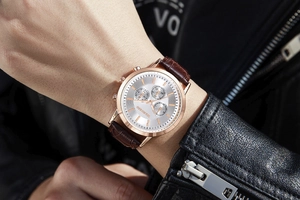 Close-up of Geneva men's multi-function watch with rose gold case and brown leather strap