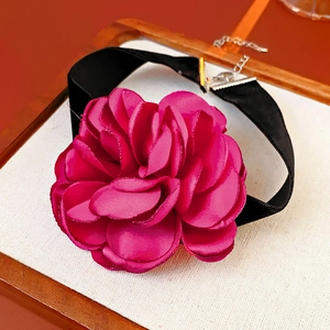 Detailed close-up of a magenta fabric flower choker with black velvet ribbon and silver clasp