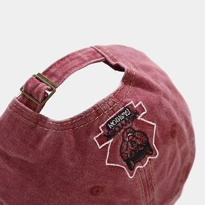Detail of washed red cotton baseball cap with embroidered husky patch and metal buckle