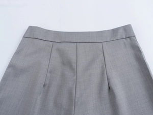 Gros plan d'un pantalon gris clair avec taille plissée et détails de couture de précision