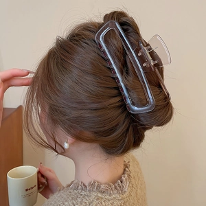 Dettaglio di un grande fermaglio per capelli in acrilico ambrato che tiene uno chignon morbido
