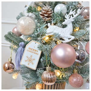 Detail of pink and champagne ornaments with reindeer and LED lights on a mini Christmas tree
