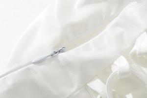 Détail de fermeture éclair invisible sur tissu satiné blanc à texture fine