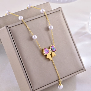 Vue macro d'un collier doré avec accents de perles et pendentif papillon en cristal coloré