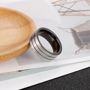 Detail of matte titanium steel ring with double black grooves on light wood surface
