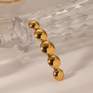 Detail of minimalist gold hair clip with five polished hemispherical metallic spheres