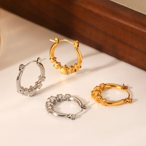 Close-up of gold and silver stainless steel hoop earrings with engraved star patterns