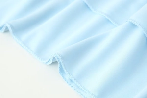Detail of light blue fabric showing professional double-stitch hem and woven texture