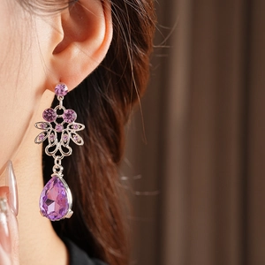 Detail of vintage silver earrings with purple floral crystals and teardrop pendants
