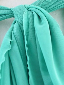 Makroaufnahme von türkisem Netzstoff-Knotendetail mit weicher Stretch-Textur und Falten