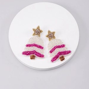Macro shot of handmade beaded Christmas tree earrings with pink stripes and gold star detail
