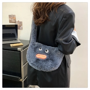 Detail of dark gray plush shoulder bag with cartoon eyes and orange lips on a model
