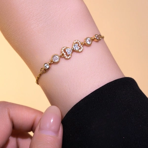 Elegant gold-plated bow bracelet with heart-shaped zirconia stones on wrist