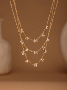 Gros plan détaillé d'un collier à trois rangs plaqué or 18k avec lettres MAMA et pendentif cœur