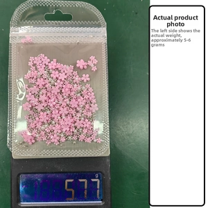 Detailed view of pink resin flowers and mini pearls nail art charms in weight test