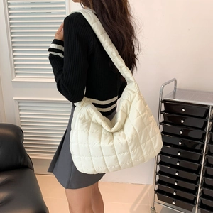 Close-up of a quilted white puffer tote bag worn on shoulder for stylish daily use