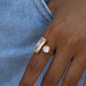 Gold stainless steel ring featuring dual square crystals worn against denim background