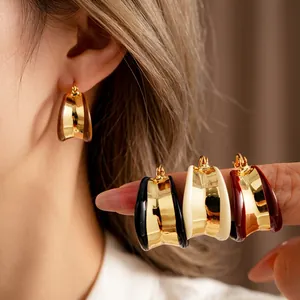 Boucles d'oreilles créoles dorées en émail noir blanc et rouge sur mannequin et main