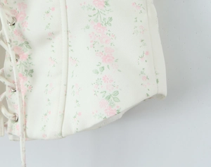 Vue macro détaillée du gilet à fleurs avec œillets métalliques et lacets en corde
