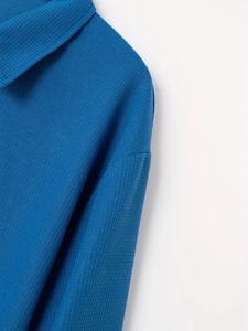 Dettaglio ravvicinato della polo da uomo blu con trama a nido d'ape e tessuto a maglia