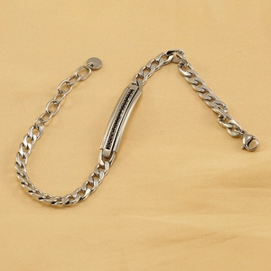 Silver stainless steel Cuban chain bracelet with black stone inlay on yellow background