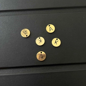 Macro shot of gold stainless steel round letter charms for DIY jewelry making