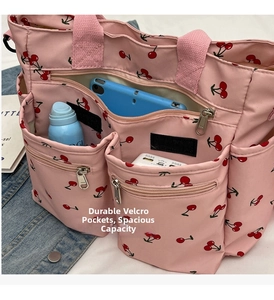 Detail of pink cherry print tote bag with multiple pockets holding tablet and essentials