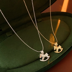 Gros plan de pendentifs cheval à bascule or et argent dans une boîte à bijoux en velours