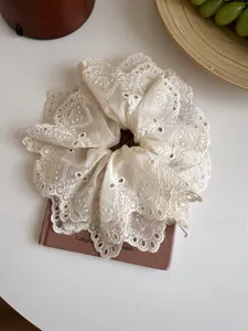 Macro view of jumbo beige lace embroidery scrunchie with floral cutouts and scalloped edges