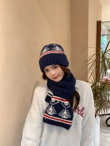 Dettaglio del set cappello e sciarpa in maglia blu scuro con motivi invernali Fair Isle