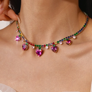 Detail of a luxury gold heart pendant with colorful zircon stones and tassels on a model
