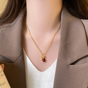 Detail of 18k gold plated necklace with red bead and gourd pendant on a model