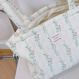 Gros plan détaillé du sac cabas matelassé à fleurs sur une chaise en métal chic
