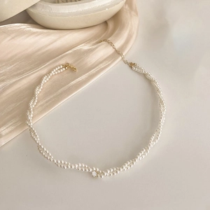 Double-layered pearl necklace with a sparkling rhinestone pendant on beige silk