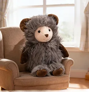 Close-up of a plush goat toy with grey long fur sitting on a miniature brown sofa