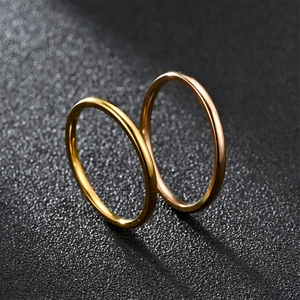 Macro shot of 2mm thin stainless steel rings in gold and rose gold finish on dark sand