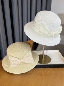 Detail of elegant French straw sun hats with wide satin bows in white and beige tones