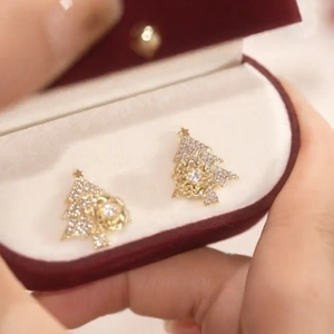 Detailed macro of golden Christmas tree studs with micro-set zircons in a red velvet box