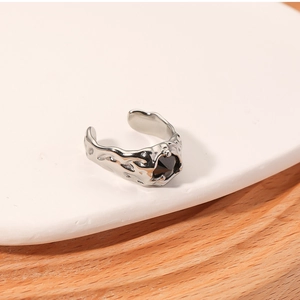Detailed view of silver irregular texture ring with black zircon on white ceramic tray