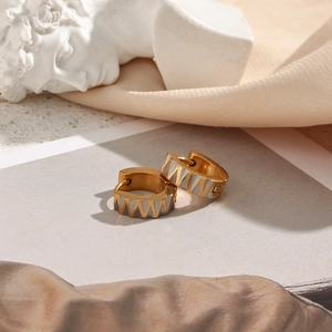 Detailed close-up of zigzag patterned earrings in gold and silver finish with square zircon