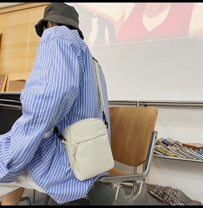 Close-up of minimalist white nylon crossbody bag with adjustable strap worn by model