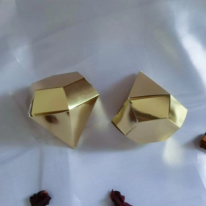 Macro detail of diamond shaped gold foil candy box on white satin background