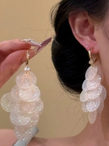 Detailed view of layered iridescent disk fringe earrings with golden metal hooks
