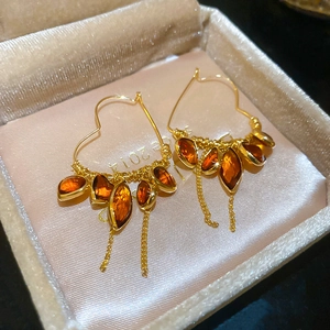 Detail view of 18K gold plated heart earrings with amber crystals and elegant tassels