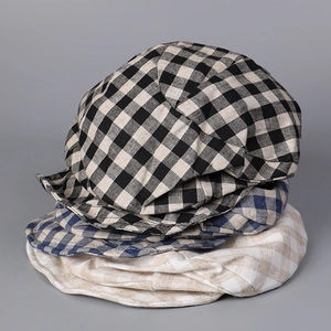 Three stacked retro plaid berets in black, blue, and beige linen fabric texture